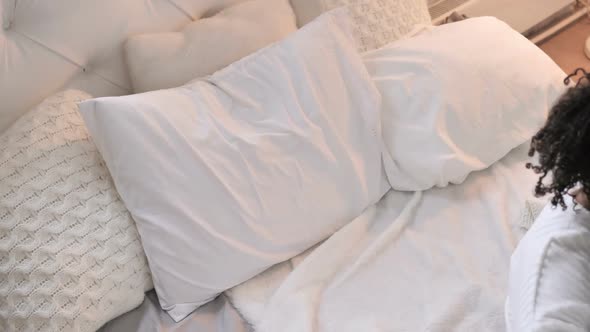 Top View of Young African Girl Waking Up in Bed alt