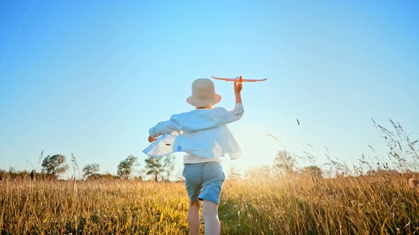 View From Back of Running Boy in Straw Panama Hat on Country Road of Summer Sunny Wheat Field with alt