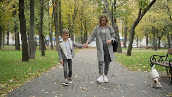 Wide Shot Portrait of Happy Caucasian Mother and Son Walking Along Park Alley on Autumn Day Outdoors alt