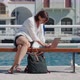 Middleaged Woman Using Laptop Sitting on Bench in the City on the Waterfront - VideoHive Item for Sale