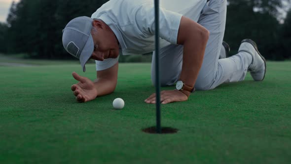 Professional Golf Player Inspect Golfing Ball Hole on Green Grass Course Field alt