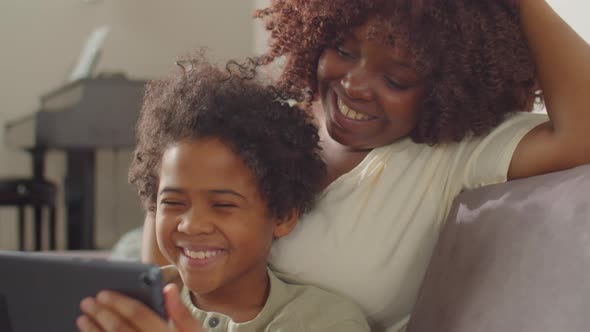 Joyous Black Mother and Little Son Using Tablet at Home alt