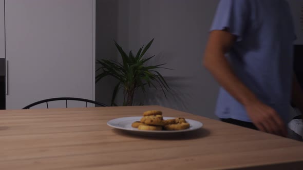 Man walking past a plate of cookies and eating all of them, concept for cravings and hunger alt