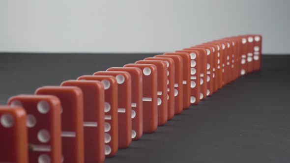 Domino Effect - a Series of Red Dominoes Falling Down the Chain alt