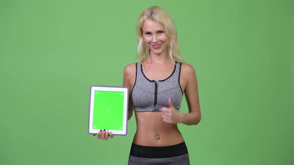 Young Happy Beautiful Woman Showing Digital Tablet and Giving Thumbs Up Ready for Gym