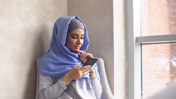 Muslim Girl Is Holding a Modern Mobile Phone. Beautiful Young Woman in Hijab