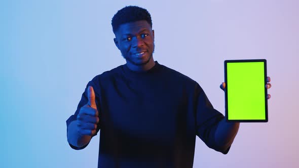 Man Holding a Digital Tablet with a Green Screen Standing in Front of the Camera alt