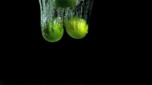 Three limes dropping into water alt