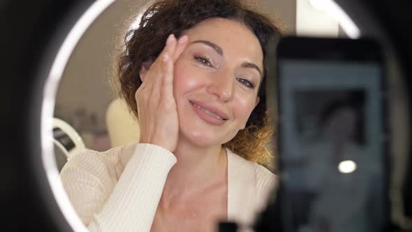 Beautiful Middle Aged Woman Demonstrates the Application of a Moisturizing and Nourishing Cosmetic