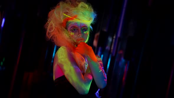 Fluorescent Cosmetic is Glowing in Darkness Model with Bright Paints on Skin and Hair alt