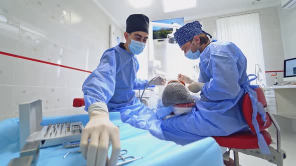 Stomatologist is Treating a Patient in a Modern Dental Office alt