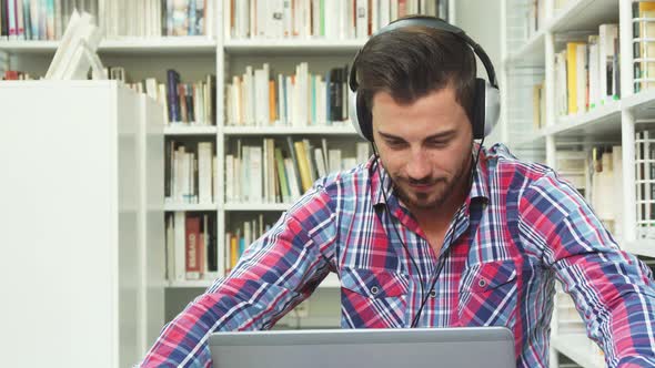 Young Guy Listening To Music on Headphones on Laptop alt