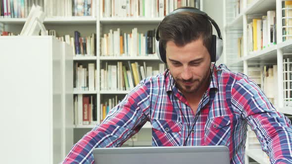 Young Guy Listening To Music on Headphones on Laptop
