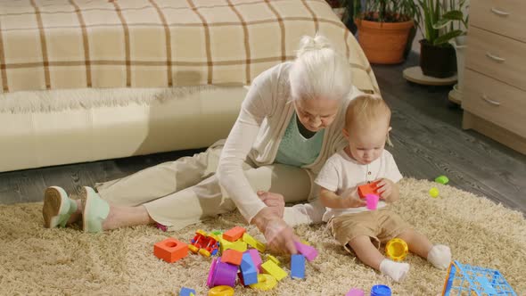 Grandmother and Baby Grandson Playing with Toys on the Floor