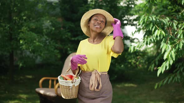 Portrait of Proud Confident African American Gardener Posing in Slow Motion with Vegetable Basket alt