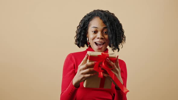 Young Happy African American Woman Catching Gift Box Enjoying Surprising Present Smiling to Camera alt