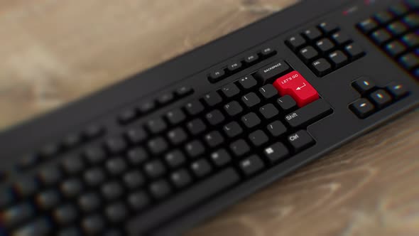 Let's Go red button on keyboard. A finger presses Enter. Click Let's Go. Close-up keyboard button. alt