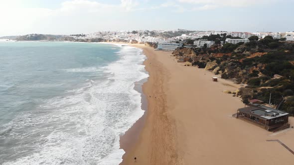 Mediterranean Beach line on sunny day in Albufeira, Algarve, Portugal - Fly-over Aerial shot alt