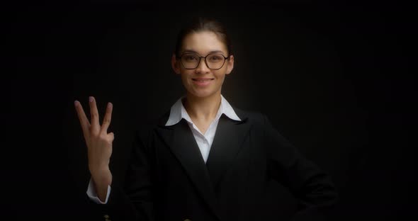 Asian Woman in Glasses Smiling and Shows Three Fingers with Her Right Hand