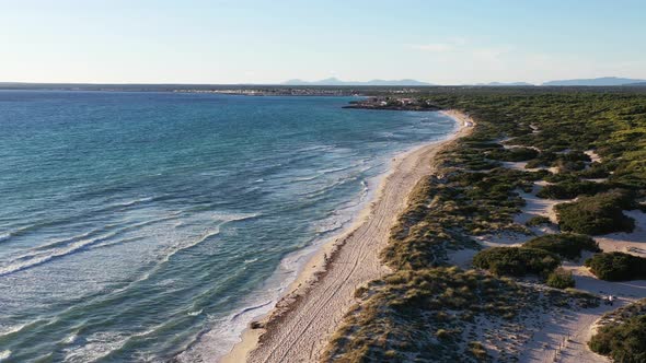 Trench Beach at the southern edge of Mallorca Island in Spain with people walking on sand, Aerial fl alt