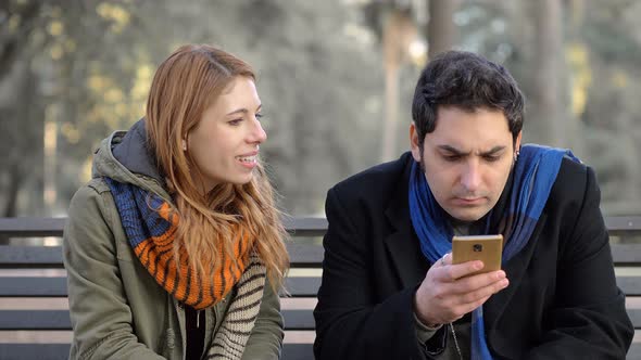 woman talking her absent-minded boyfriend using smartphone,starting fight alt