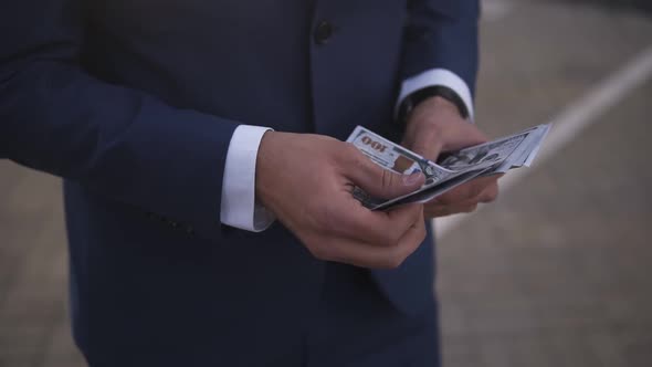 Solid Rich Businessman on the Street Holding Bundle of American Money in His Hands Counting It alt