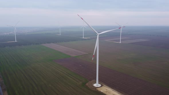 Aerial View of Wind Turbines and Agriculture Field Near the Sea at Sunset alt