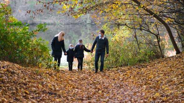 Family Parents with Children in Medical Masks Walk in the Park on an Autumn Day