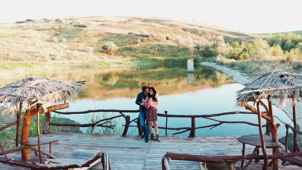 Flying Over a Couple Tasting Wine on Pontoon Near a Lake alt