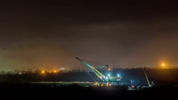 An excavator works at night in an open pit, time lapse.