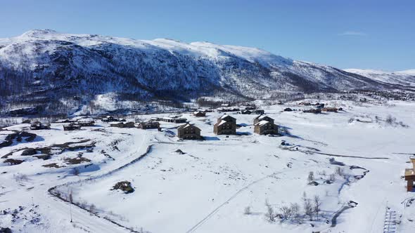 Maurset Hardangervidda Norway - Aerial showing vacation homes in between snowy mountains close to rv alt