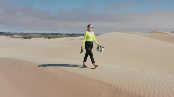 Beautiful Woman in Neon Futuristic Costume and VR Glasses Walking By Sand Dunes alt