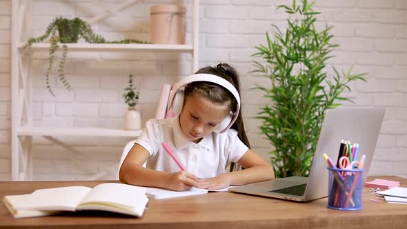 Little Child Girl Using Laptop for Doing School Tasks at Home and Writing Notes.