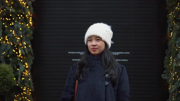 Pretty Asian Girl is Standing Beside Trees Decorated for Christmas