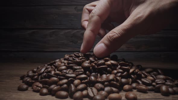 Human Hand touching Roasting brown Coffee Beans with steam. tracking shot, close up