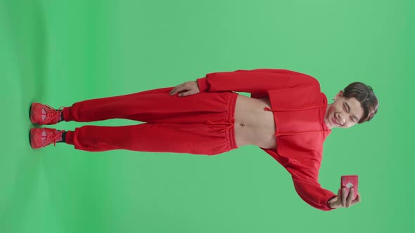 Full Body Of The Smiling Asian Transgender Male Making Selfie While Standing On Green Screen alt