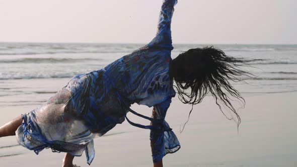 Young Gymnast Woman Doing Handspring on Sandy Beach
