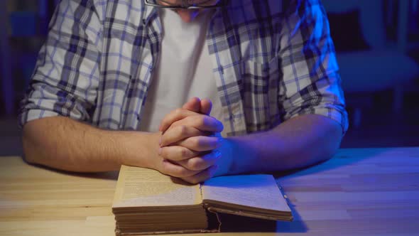 Close Up Man Sits at a Table and Reads a Prayer alt