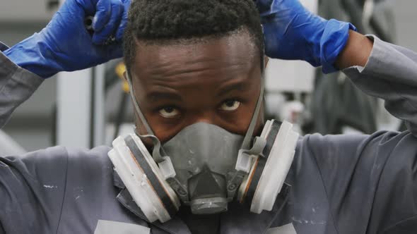 African American male car mechanic putting on a face mask alt