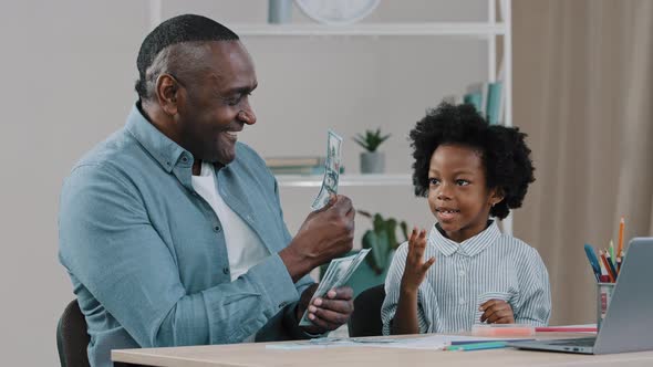 African American Father Helps to Do Homework Teaches Little Daughter Arithmetic Using Dollar Bills alt