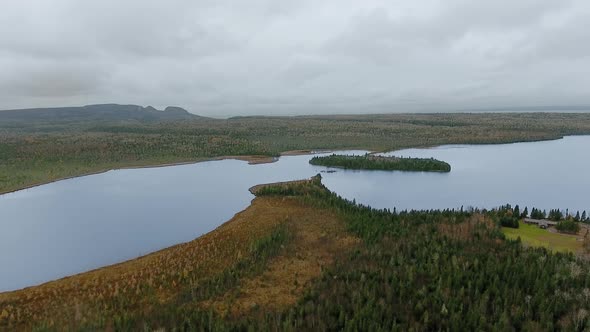 Footage of lake between wooded shores, cottage and mountains in Marie Louise Lake, Ontario, Canada alt