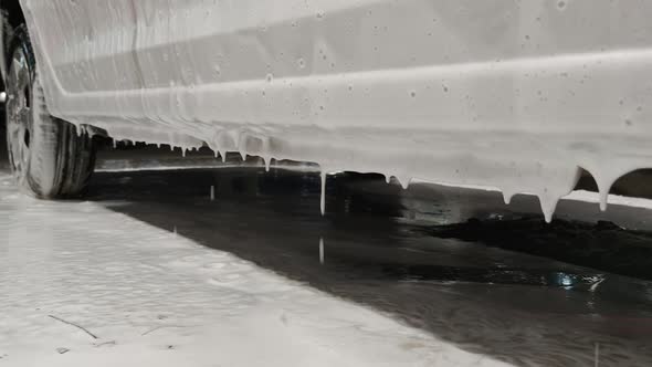 White Soap Sud Falling Down From Car Door During Car Wash Procedure at Night Station Closeup alt