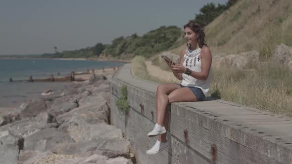 Young Attractive Woman Sat At The Beach Receives A Phone Call From A Close Friend In Slowmotion - Un alt