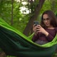A Young Woman Lies in a Hammock and Communicates on the Internet Through the Phone - VideoHive Item for Sale