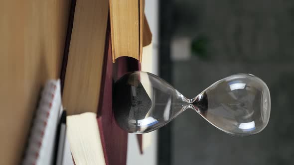 Vertical Video Shot of a Sand Clock Measuring Time While the Sand is Falling Down Against the Black alt