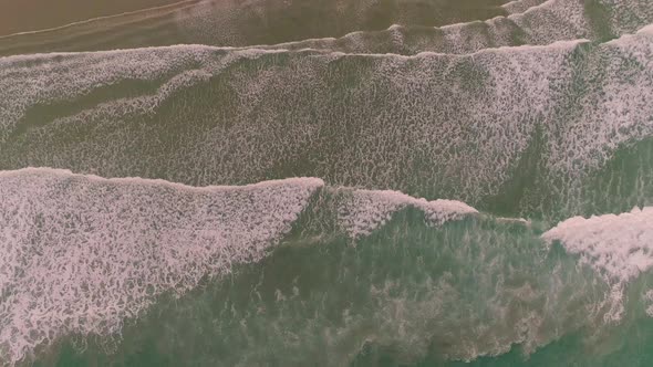 Top down Aerial drone view of waves coming in to the beach. Slow pull up. alt