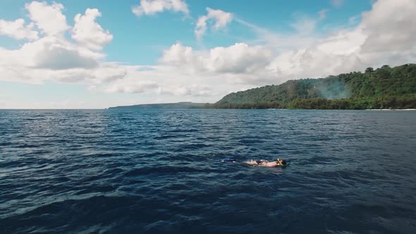 Aerial View on Woman Snorkeling on Surface of Tropical Sea Under Beautiful Sky alt