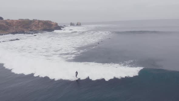 Aerial shot following Surfer riding a wave at Punta de Lobos, Chile-4k alt