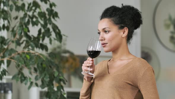 Side View of Young African American Woman Drinking Red Wine From Glass Goblet alt