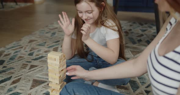 Mother and Daughter Build Tower From Wooden Bricks Sitting on a Floor at Home alt